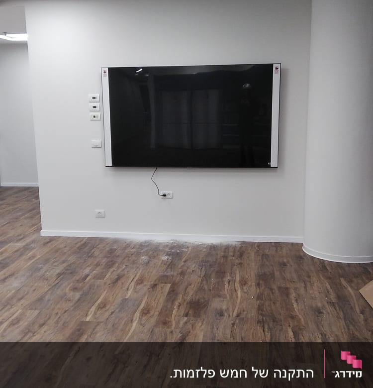 טלוויזיה תלויה על קיר עם כבל חשמל חשוף